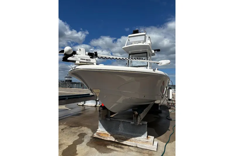 Slide: The Image of 2023 Robalo 246 Cayman SD boat on dry dock under a partly cloudy sky. - 5