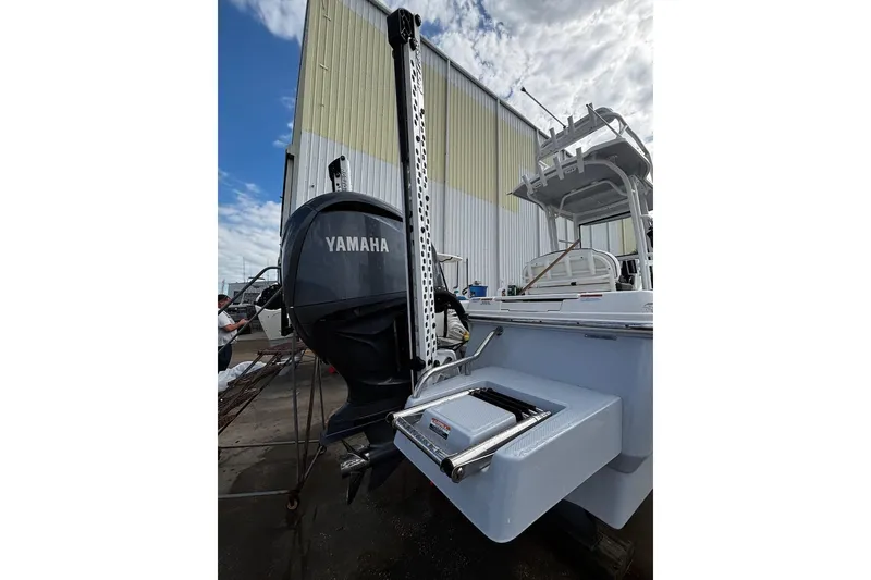 Slide: The Image of 2023 Robalo 246 Cayman SD boat with Yamaha engine, docked near a warehouse. - 51
