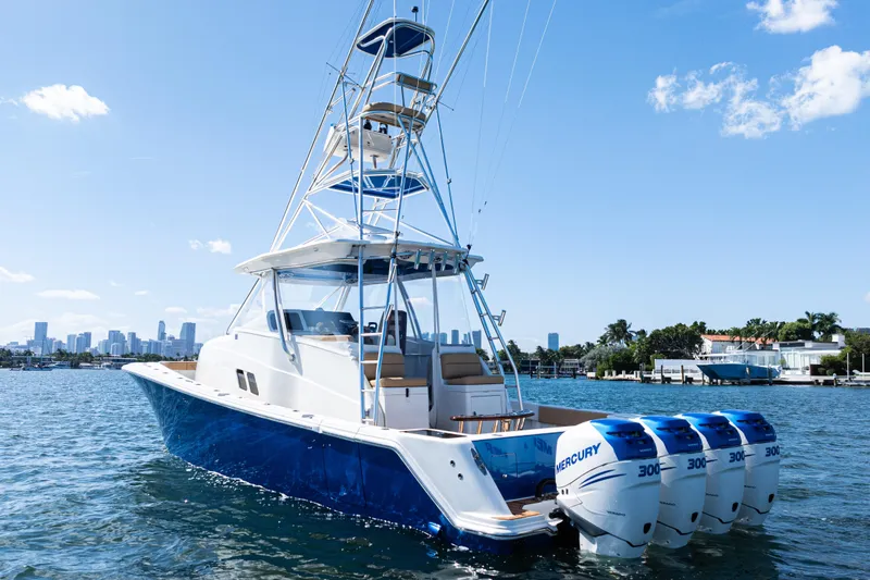 Slide: The Image of 2016 SeaVee 430 boat on water, blue hull, clear sky, waterfront homes in background. - 2