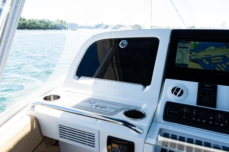 Slide: The Image of 2016 SeaVee 430 boat dashboard with navigation screen and cup holders, overlooking water. - 33