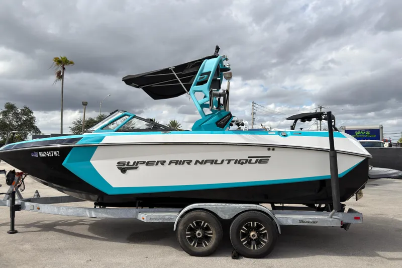 Slide: The Image of 2019 Nautique Super Air Nautique G23 Coastal Edition boat on trailer, under cloudy sky. - 10