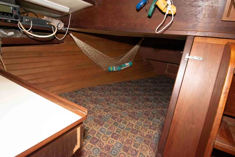 Slide: The Image of 1985 Morgan 384 yacht interior with wood paneling, hammock, and patterned carpet. - 7