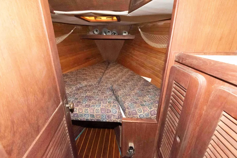 Slide: The Image of 1985 Morgan 384 sailboat cabin with wooden interior and patterned bedding. - 9