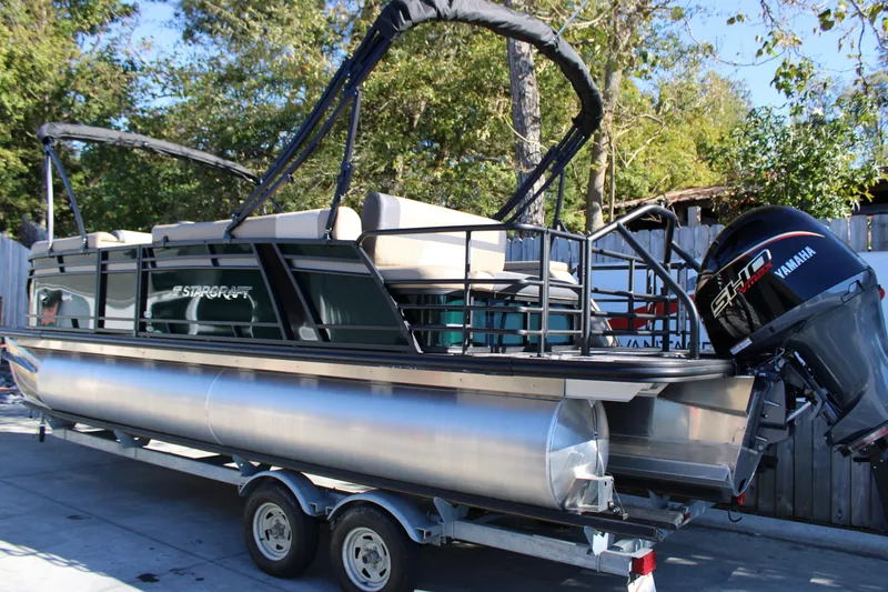 Slide: The Image of 2026 Starcraft EXS 3 Q pontoon boat on trailer with Yamaha engine, parked outdoors. - 3
