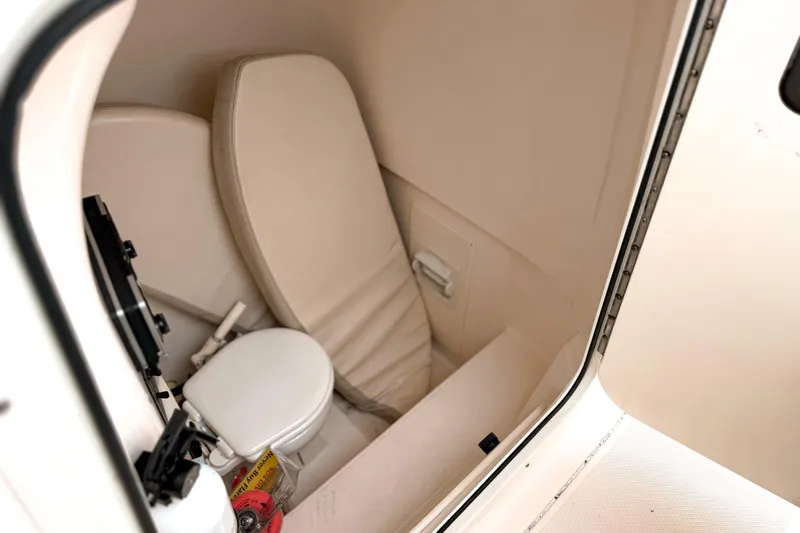 Slide: The Image of 2014 Pursuit S 280 Sport boat interior with compact toilet and seating area. - 18