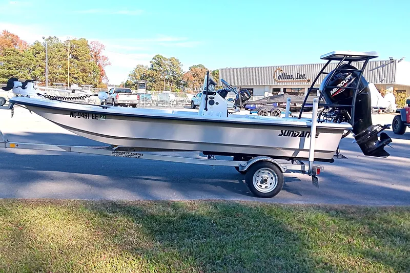 Slide: The Image of 2014 Sundance K16CC boat on trailer, parked outdoors near dealership. - 0