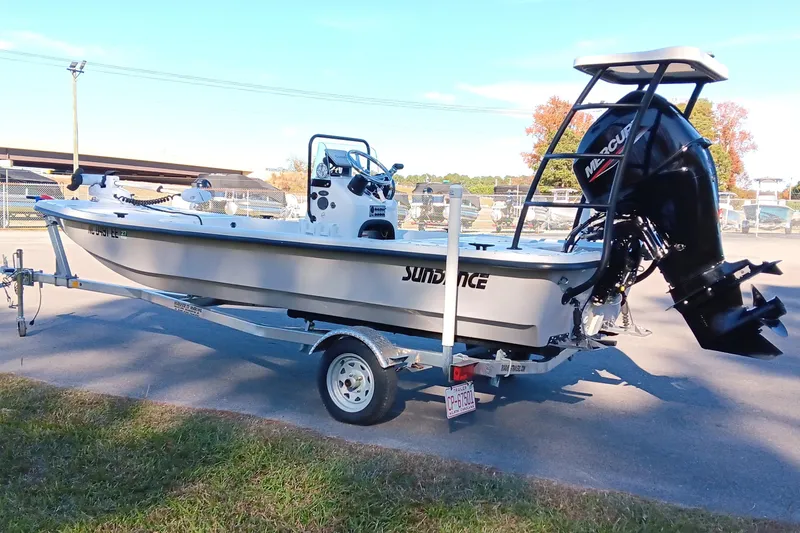 Slide: The Image of 2014 Sundance K16CC boat on trailer with Mercury outboard motor, parked outdoors. - 2