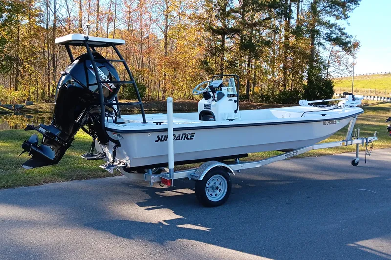Slide: The Image of 2014 Sundance K16CC boat on trailer, parked outdoors with autumn trees in background. - 4