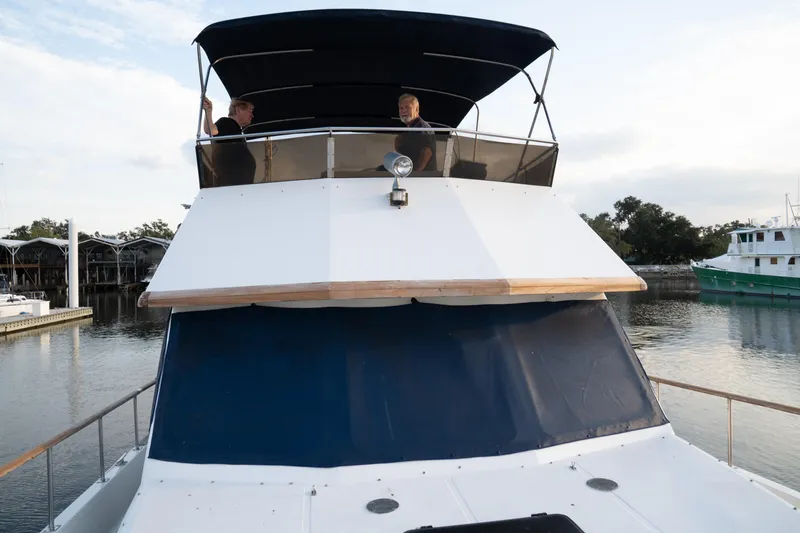 Slide: The Image of 1991 Marine Trader 46 fast trawler docked, featuring upper deck with two people. - 11