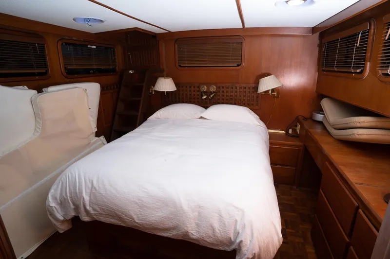 Slide: The Image of Cozy bedroom interior of 1991 Marine Trader 46 fast trawler with wood paneling and white bedding. - 28