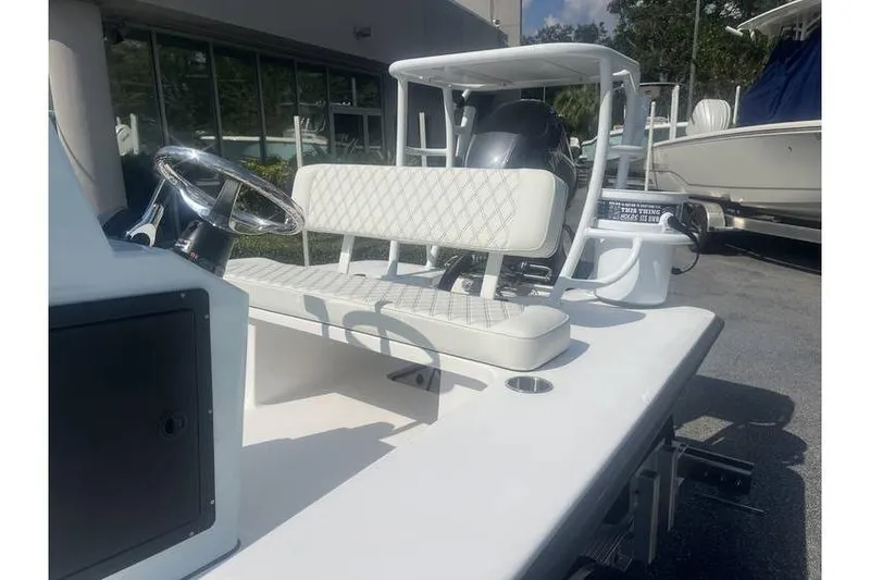 Slide: The Image of 2026 Delta Boatworks D18 with white seating and steering wheel, docked outdoors. - 5