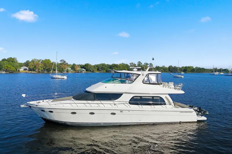Slide: The Image of 2006 Carver 56 Voyager yacht on a serene lake with clear blue skies. - 1