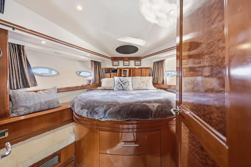 Slide: The Image of Luxurious 2006 Carver 56 Voyager yacht bedroom with plush bedding and elegant wood finishes. - 28