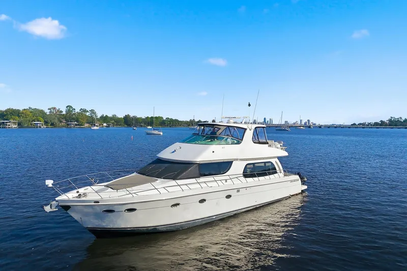 Slide: The Image of 2006 Carver 56 Voyager yacht cruising on a serene blue lake under a clear sky. - 3