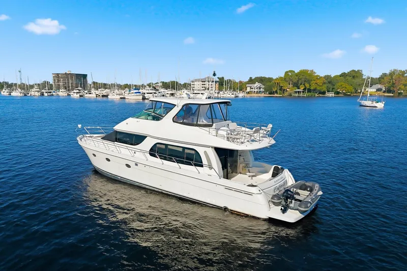 Slide: The Image of 2006 Carver 56 Voyager yacht on serene blue water, marina in background. - 5