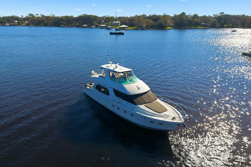 Slide: The Image of 2006 Carver 56 Voyager yacht cruising on a sunny lake with scenic shoreline. - 7