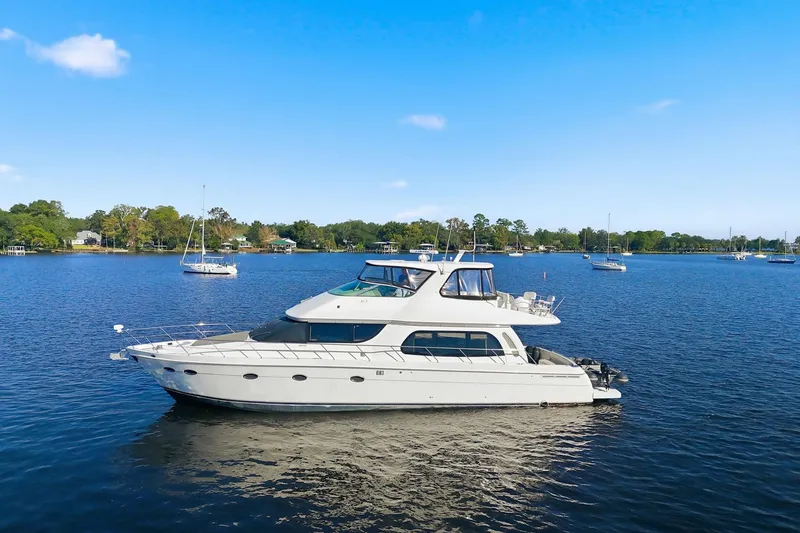Slide: The Image of 2006 Carver 56 Voyager yacht on a serene lake with clear blue skies. - 9