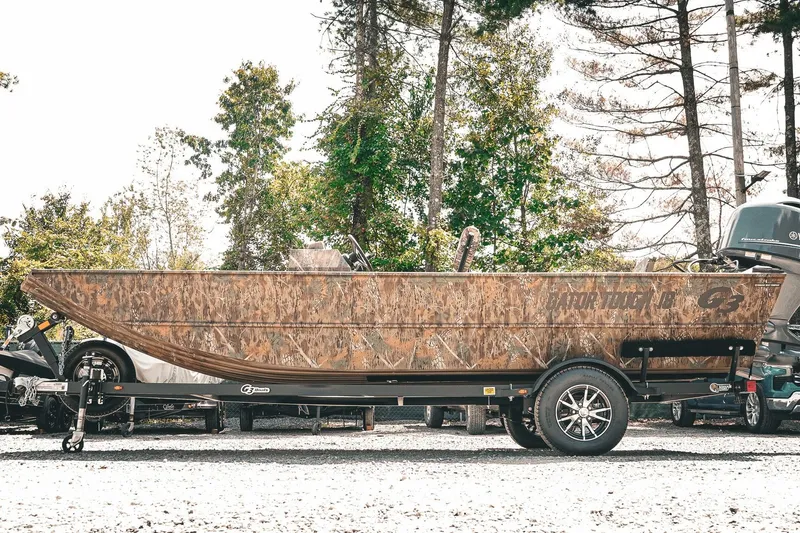 Slide: The Image of 2026 G3 Gator Tough 18 CCJ boat on trailer, camo design, outdoors. - 4