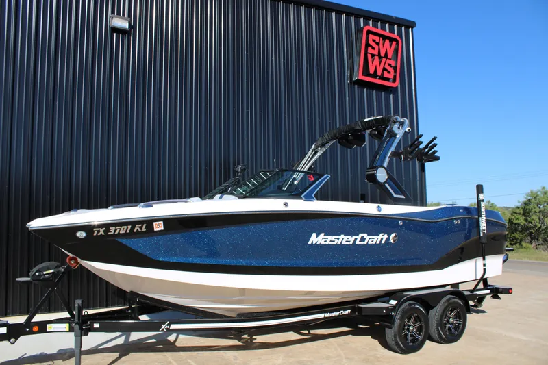Slide: The Image of 2022 MasterCraft X24 boat in blue, parked outside SWWS building. - 4