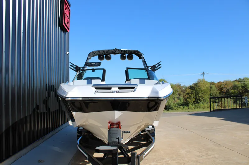 Slide: The Image of 2022 MasterCraft X24 boat on trailer, parked outdoors near a black building. - 6