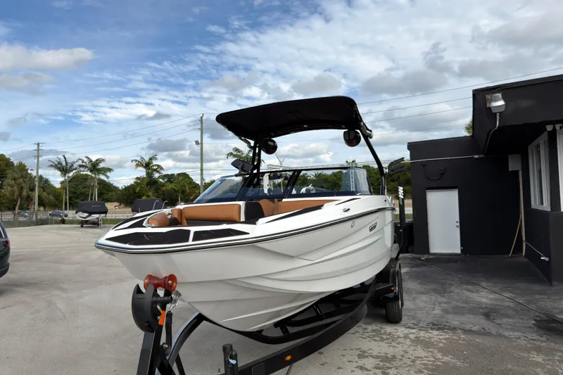 Slide: The Image of 2025 Supreme S220 boat on trailer, parked outdoors under cloudy sky. - 13