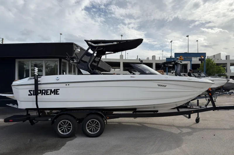Slide: The Image of 2025 Supreme S220 boat on trailer, sleek white design, parked outdoors. - 3