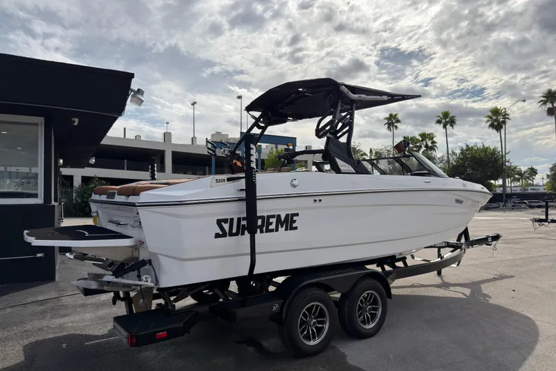 Slide: The Image of 2025 Supreme S220 boat on trailer, parked outdoors under cloudy sky. - 4
