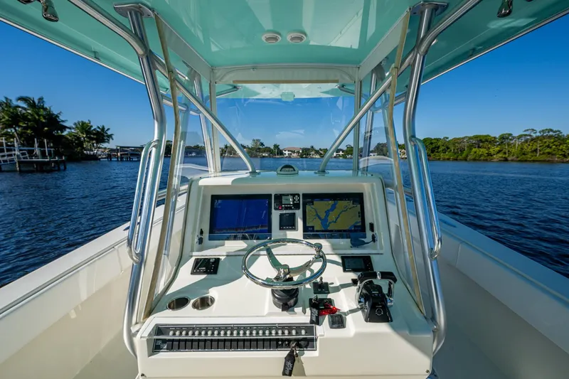 Slide: The Image of 2017 SeaVee 390Z boat cockpit with navigation screens, steering wheel, and controls on a sunny day. - 13