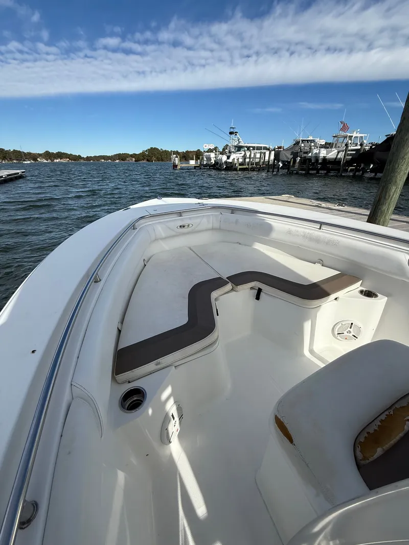 Slide: The Image of 2012 Sea Hunt Triton 240 boat interior with seating, docked by the water under a blue sky. - 10