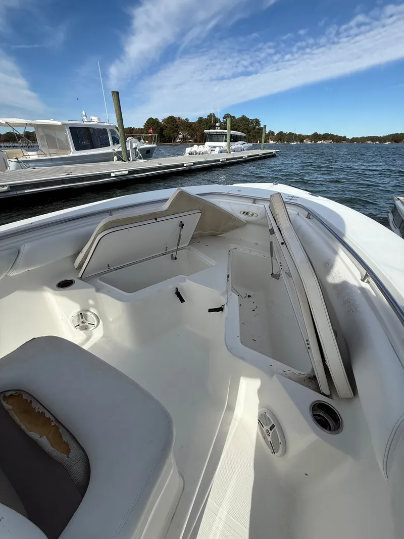 Slide: The Image of 2012 Sea Hunt Triton 240 boat interior with open storage compartments at a marina. - 12