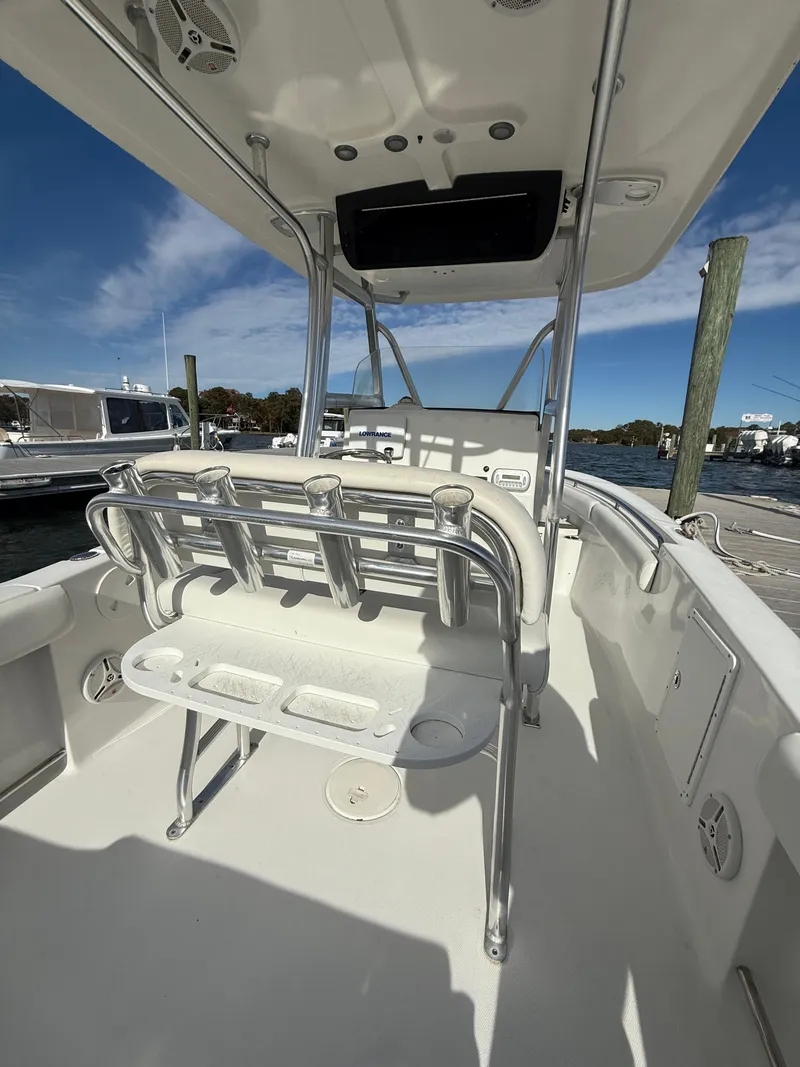 Slide: The Image of 2012 Sea Hunt Triton 240 boat interior with rod holders and seating, docked under clear sky. - 16