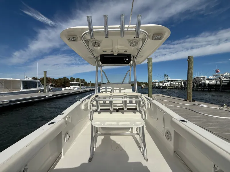 Slide: The Image of 2012 Sea Hunt Triton 240 boat docked, showcasing spacious deck and T-top under clear sky. - 17