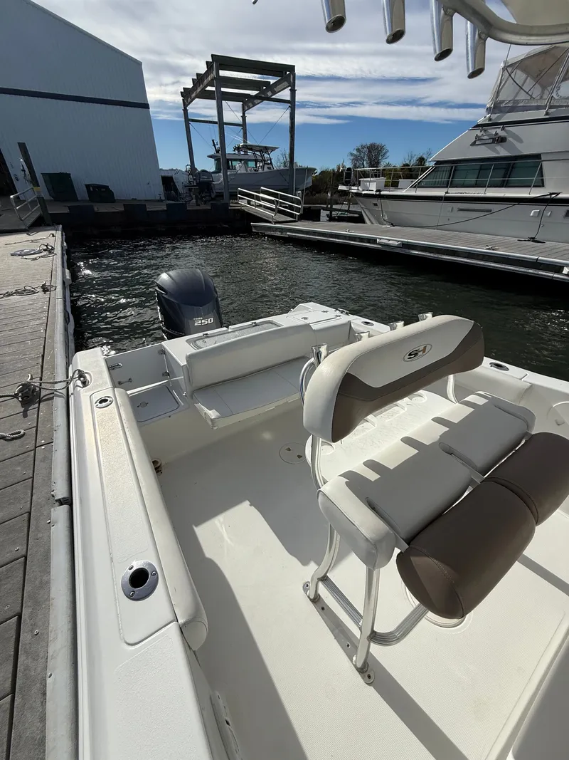 Slide: The Image of 2012 Sea Hunt Triton 240 boat docked, featuring seating and outboard motor. - 9