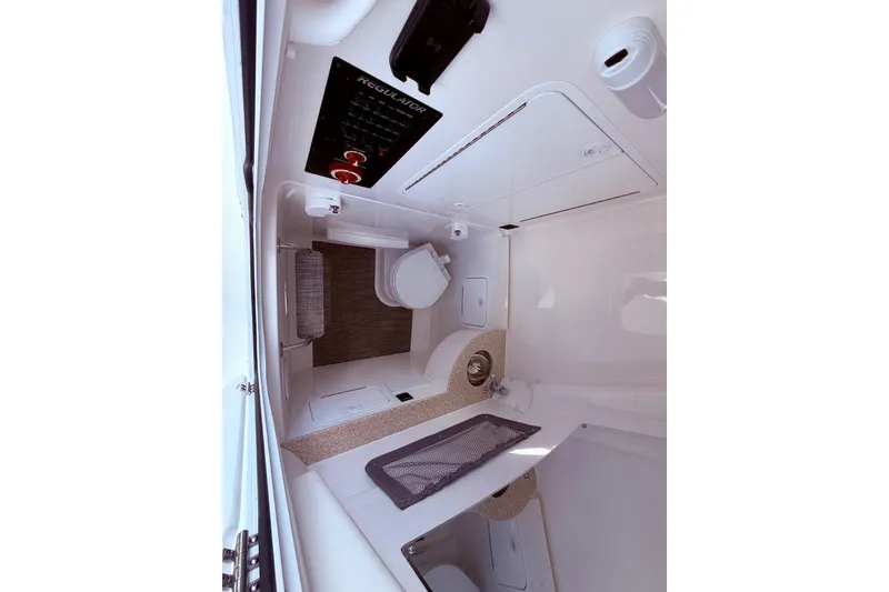 Slide: The Image of Interior of 2026 Regulator 28 boat featuring a compact bathroom with toilet and sink. - 37
