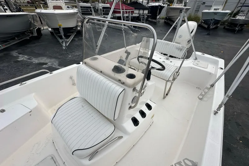Slide: The Image of 2001 Century 2101 Bay Boat with white seating and steering console, parked among other boats. - 15