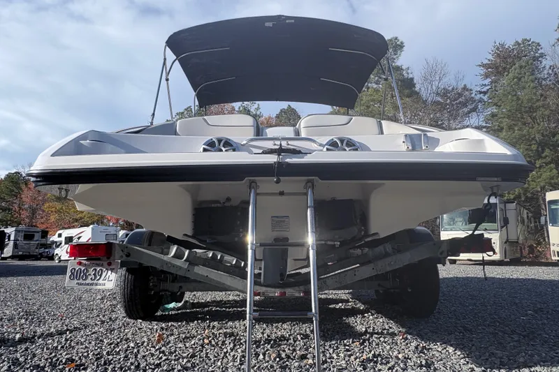 Slide: The Image of 2019 Yamaha Boats SX210 on trailer, rear view with canopy, parked on gravel. - 4
