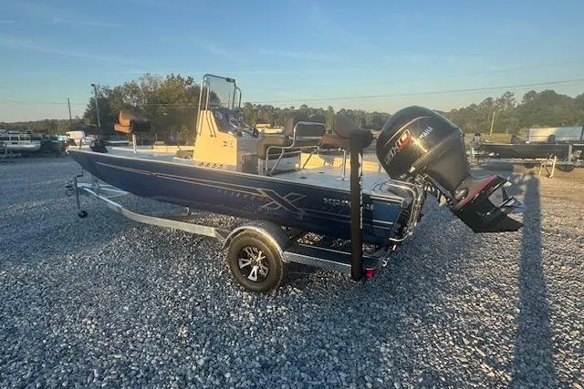 Slide: The Image of 2026 Xpress H20B Bay boat on trailer, parked on gravel lot under clear sky. - 10