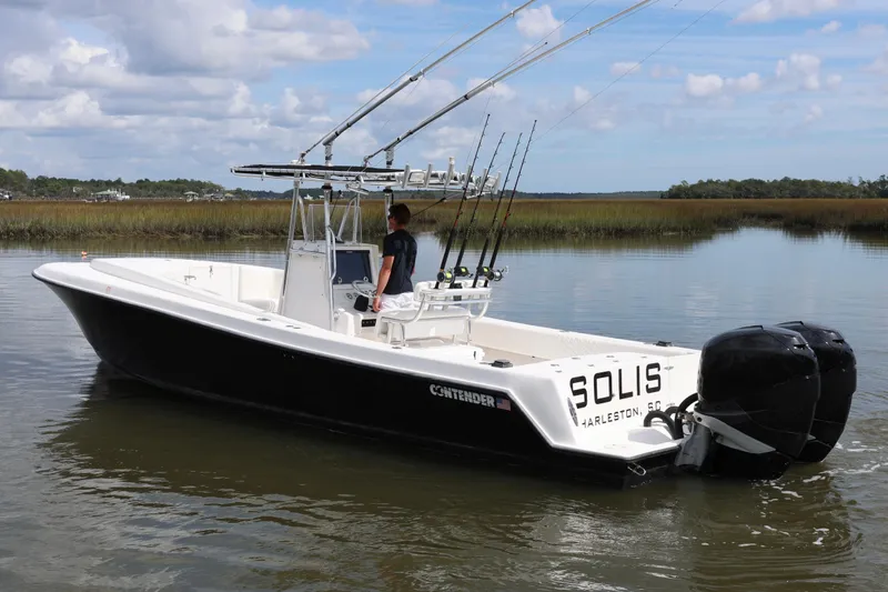 Slide: The Image of 2005 Contender 31 Cuddy boat on a calm river with a person onboard. - 2