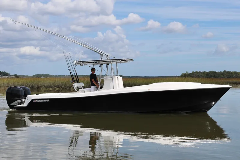 Slide: The Image of 2005 Contender 31 Cuddy boat interior with fishing rods and dual engines on open water. - 8