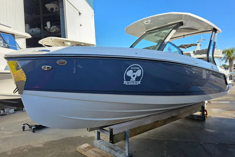 The Image of 2026 Monterey Elite 25 OB boat displayed outdoors on a stand. - 0