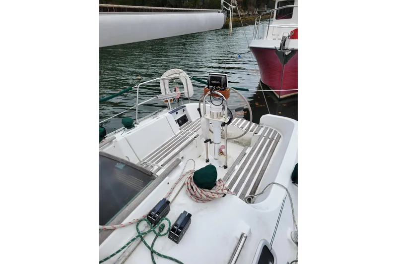 Slide: The Image of 1994 Beneteau Oceanis 300 sailboat cockpit with steering wheel and ropes, docked on calm water. - 12
