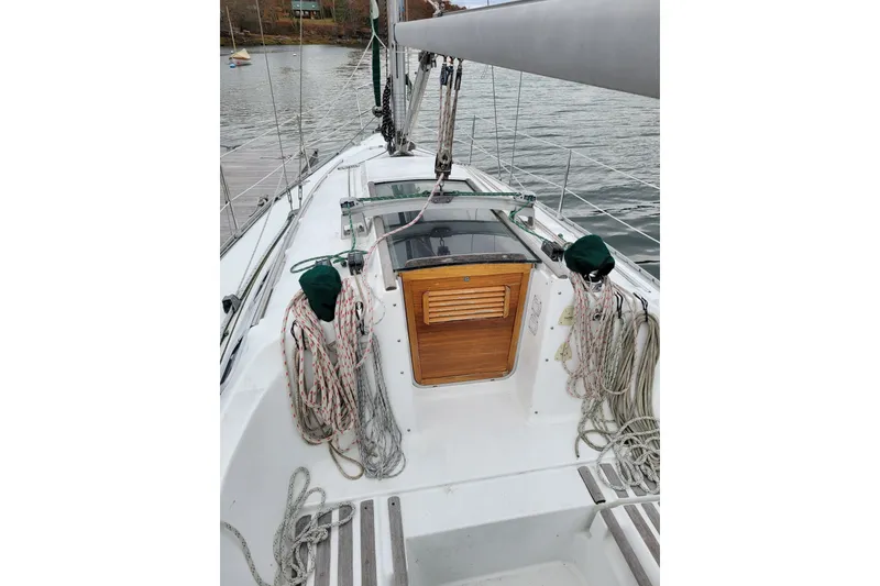 Slide: The Image of 1994 Beneteau Oceanis 300 sailboat cockpit with ropes and wooden hatch, docked on calm water. - 16