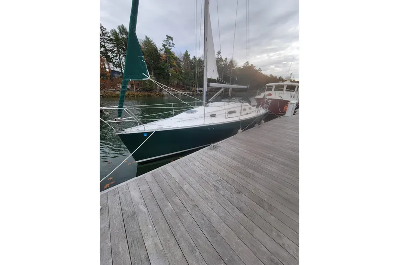 Slide: The Image of 1994 Beneteau Oceanis 300 sailboat docked by a wooden pier, surrounded by trees. - 3