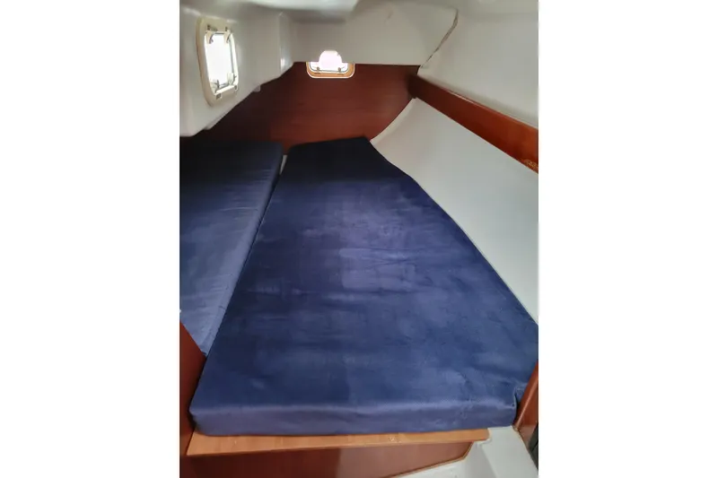 Slide: The Image of 1994 Beneteau Oceanis 300 cabin interior with blue cushions and wooden accents. - 8