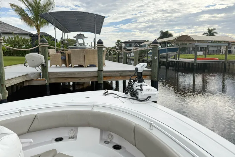Slide: The Image of 2023 Sportsman Open 322 Center Console boat docked by a scenic waterfront. - 11