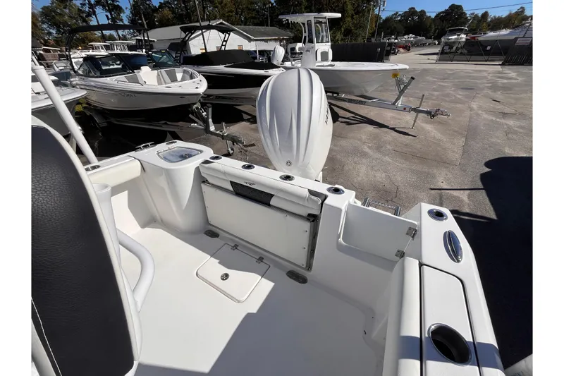 Slide: The Image of 2026 Tidewater 232 CC Adventure boat interior with outboard motor, docked among other boats. - 4