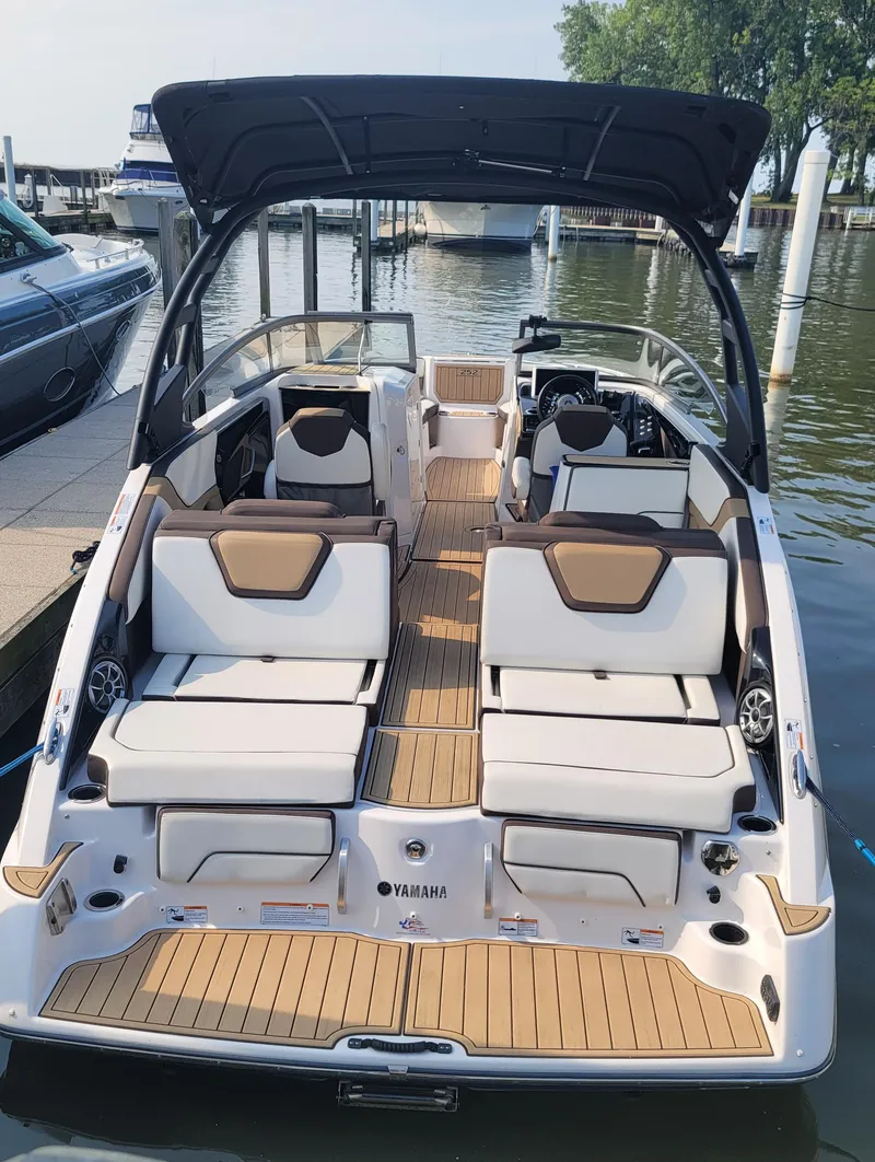Slide: The Image of 2021 Yamaha Boats 252SD, luxury interior, docked at marina, featuring spacious seating and modern design. - 12