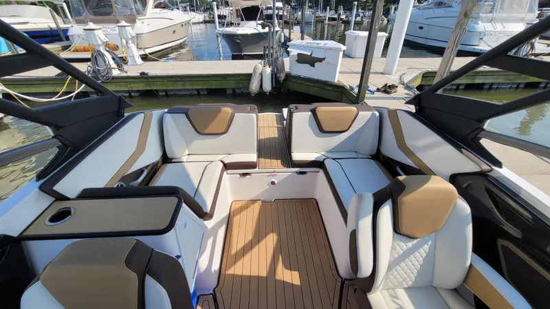Slide: The Image of 2021 Yamaha Boats 252SD interior with luxurious seating at a marina. - 15