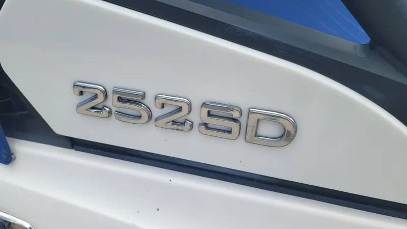 Slide: The Image of 2021 Yamaha Boats 252SD docked, covered with blue canopy and cover, in a marina setting. - 2