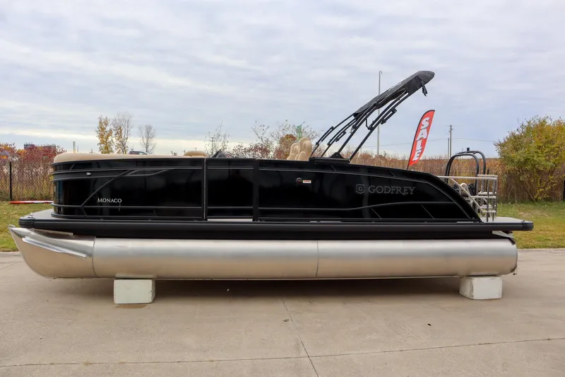 Slide: The Image of 2026 Godfrey Monaco 235 SFL pontoon boat on display outdoors, sale sign visible. - 2